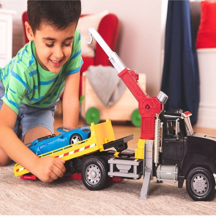 Kid playing with crane truck and car