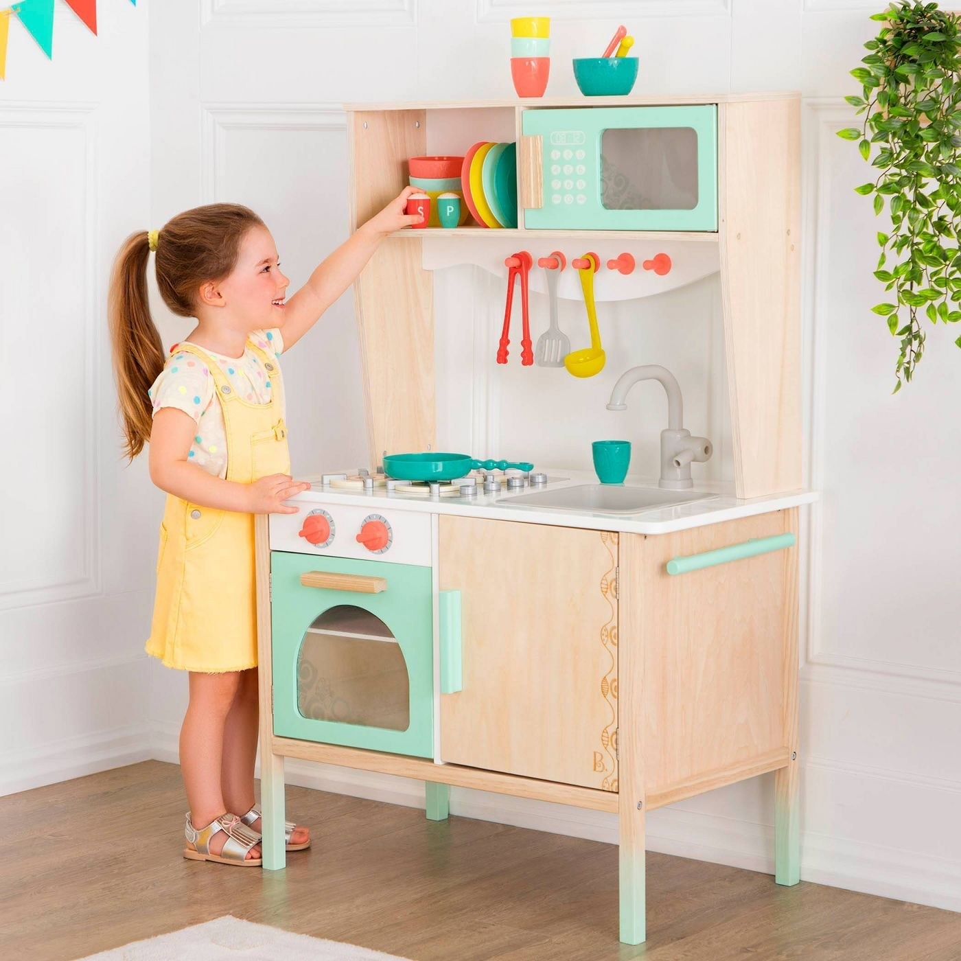 A kid that is playing with a wood kitchen