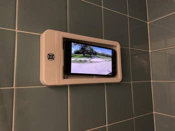 Reviewer photo of the shower mount with a phone inside playing a video