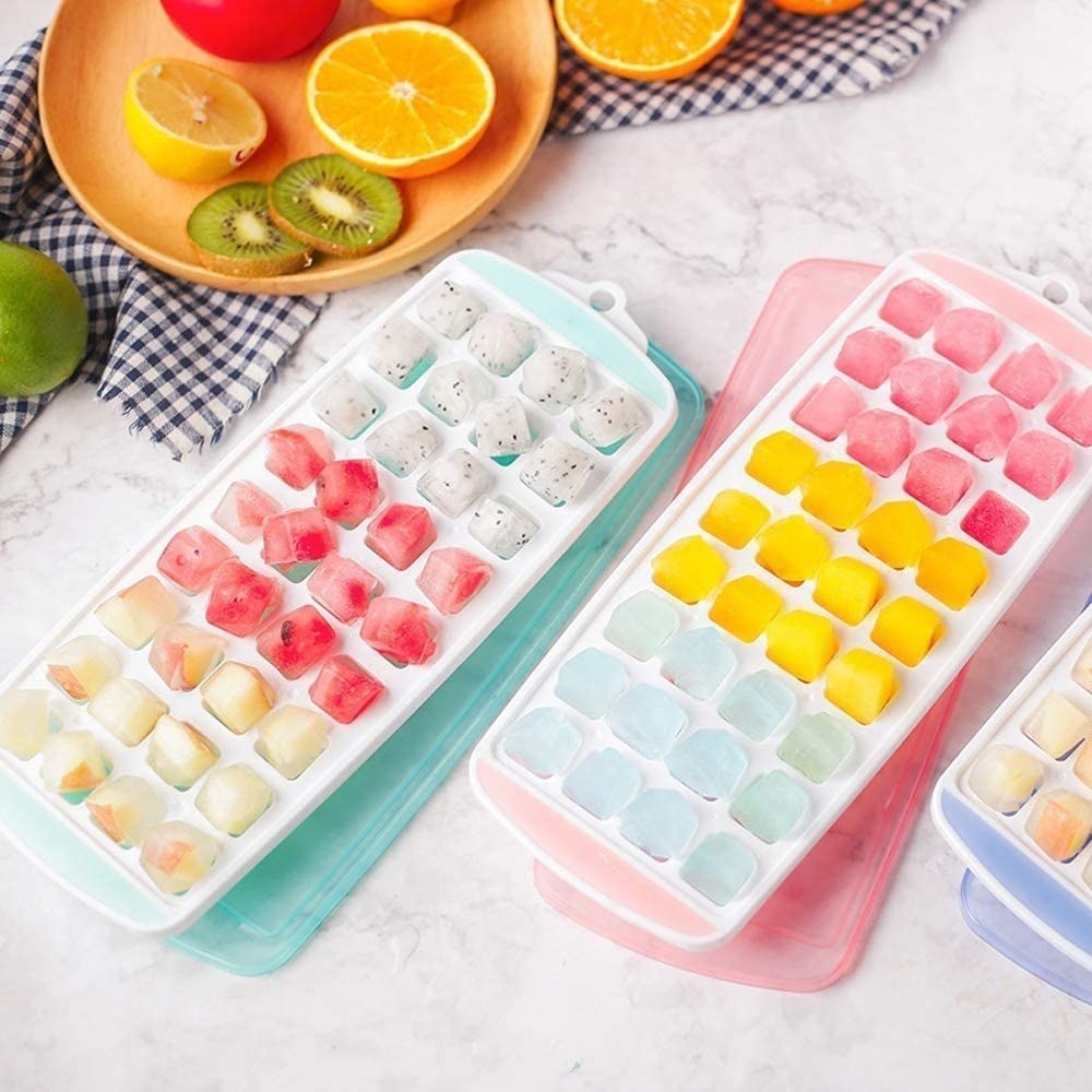 teal and pink small-sized ice cube tray filled with frozen cubes of ice and fruit juice