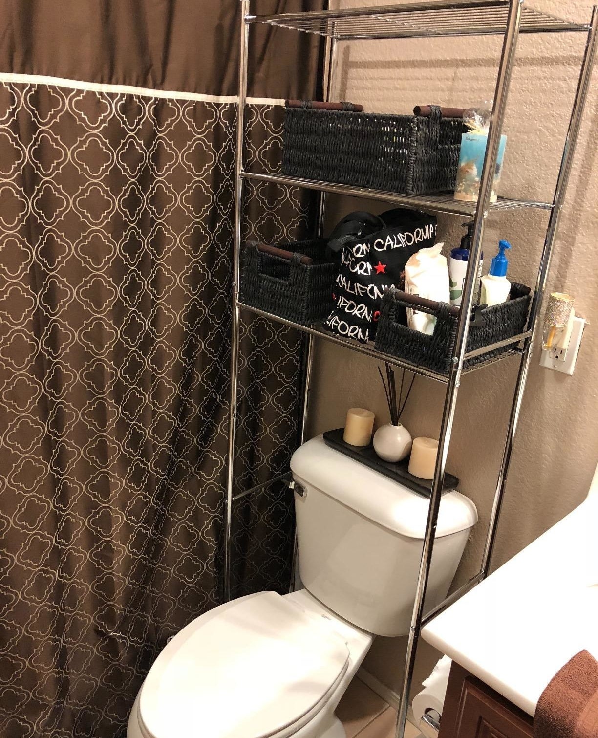 a reviewer photo of the rack over their toilet with storage baskets on it