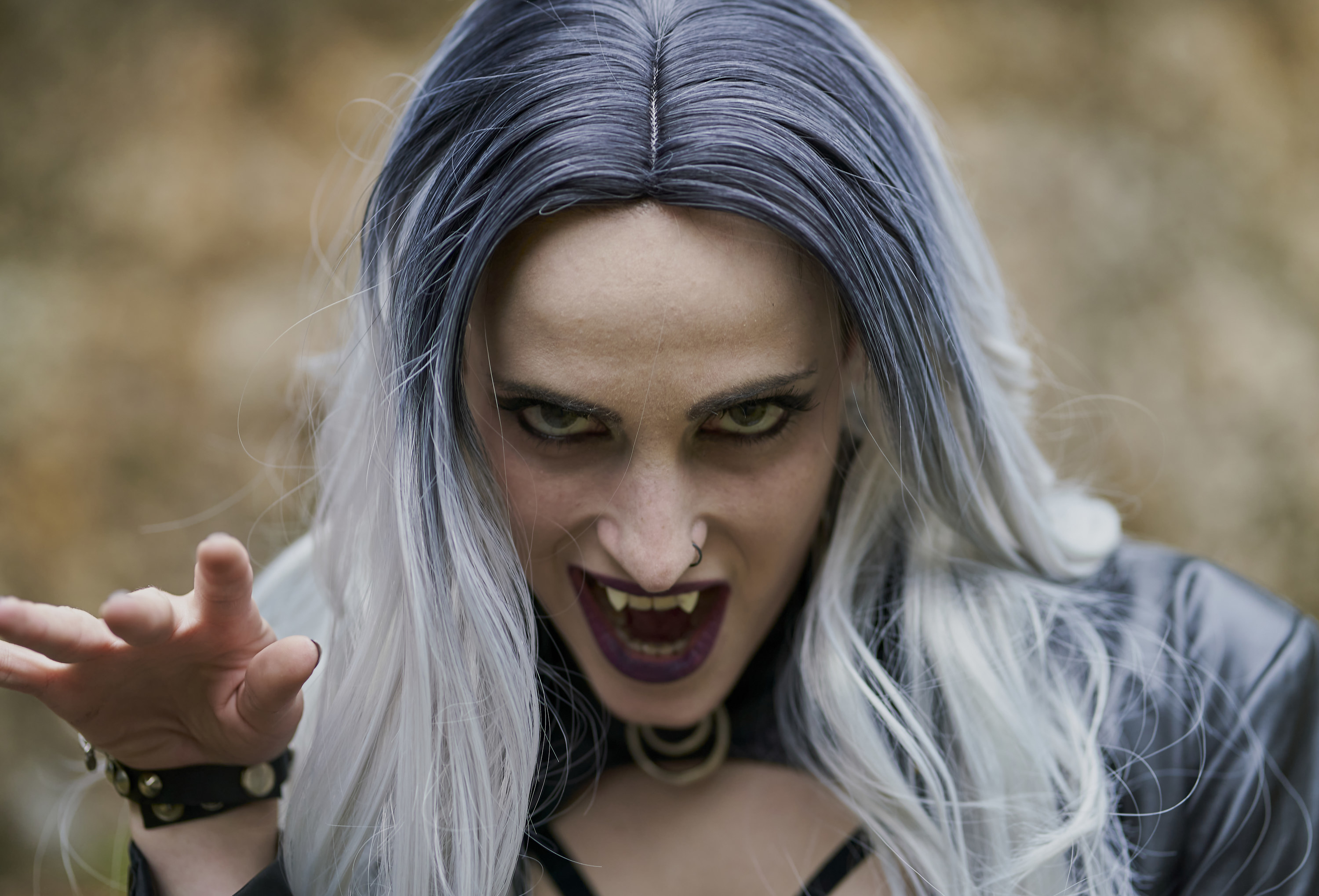 Portrait of woman in a vampire costume and opening her mouth to show the fangs