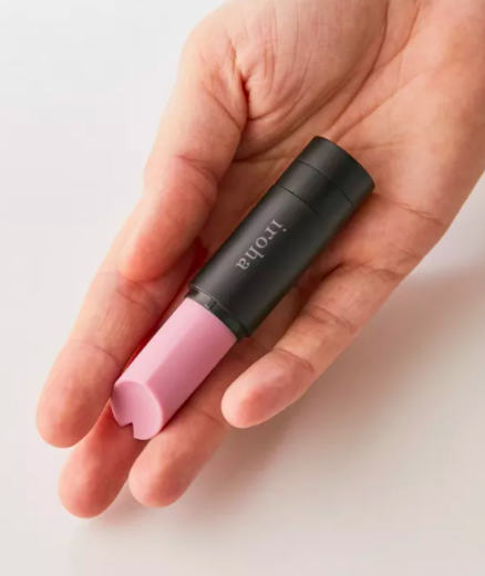 A person holding the lipstick-shaped vibrator in their outstretched palm