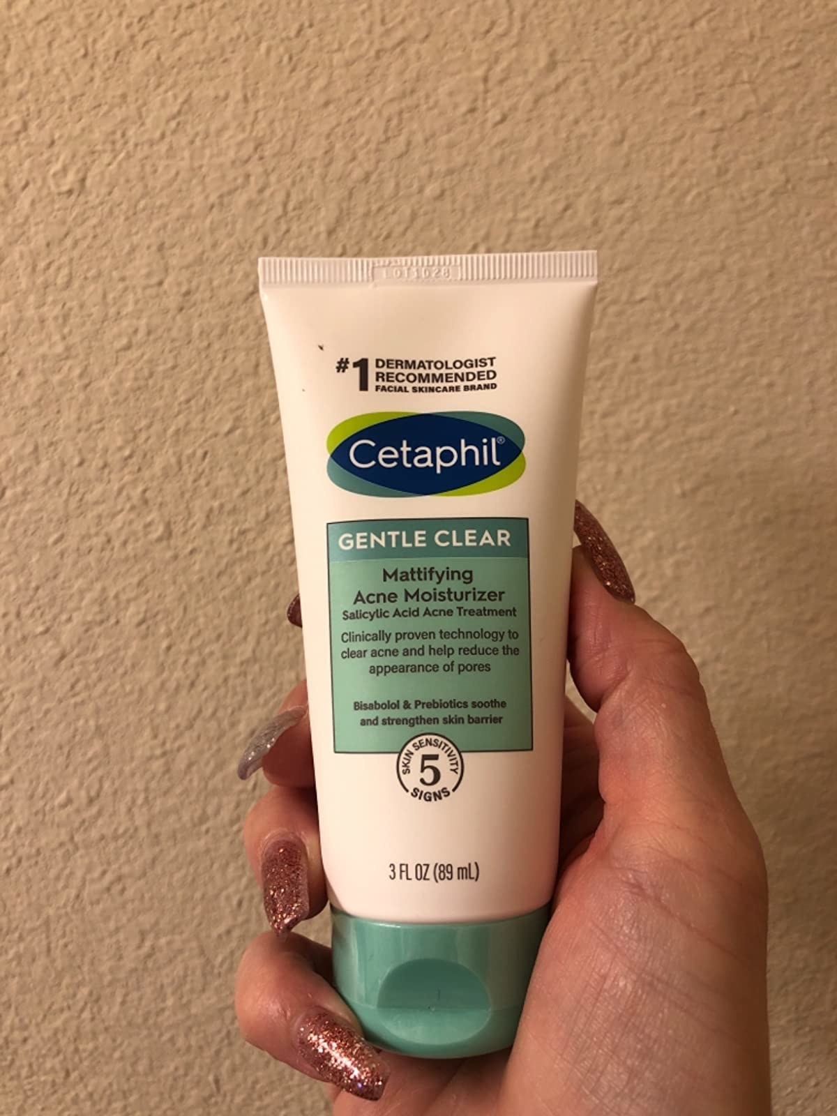 reviewer holding tube of Cetaphil acne cleanser in hand