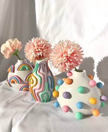 small vases with colorful dots, rainbows, and squiggly lines holding pink flowers