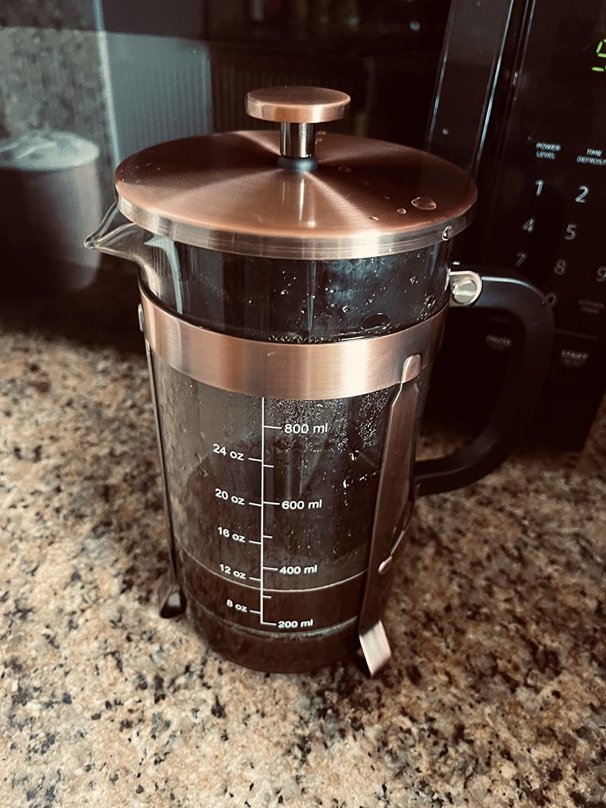 reviewer image of an almost empty copper French press on a granite countertop