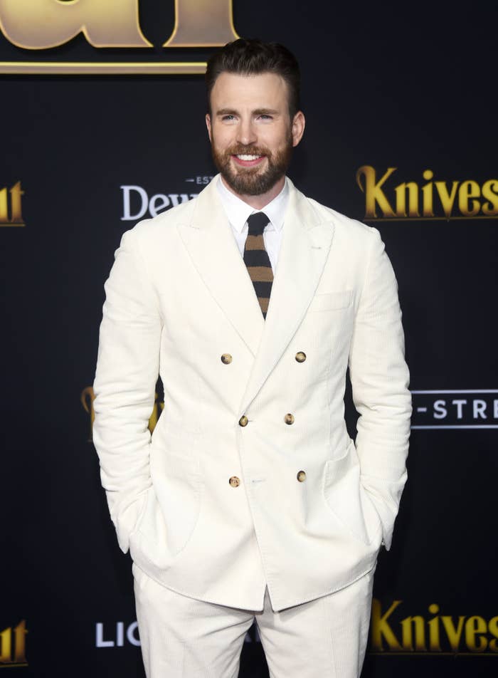 Chris Evans in a light-colored suit and a striped tie at the premiere of Knives Out