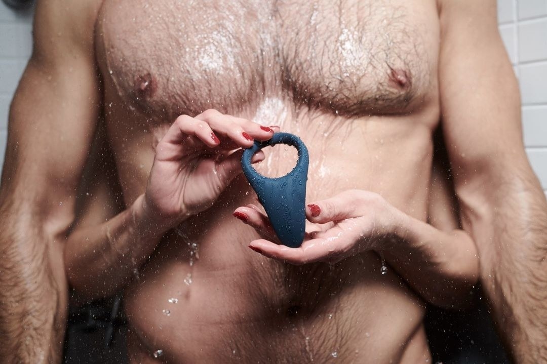 someone holding the vibrating ring in front of a wet naked torso