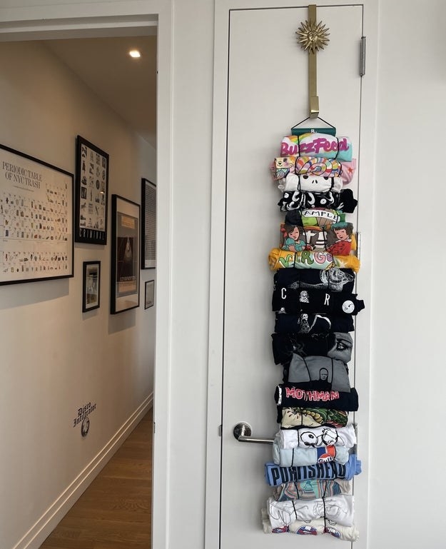 a reviewer photo of a closed closet with several shirts hanging from a hook at the top of the door. The shirts are attached by rolling them up and putting them through stretchy loops.