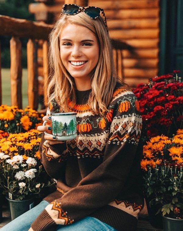 a model in a brown sea isle sweater with a pumpkin design on it