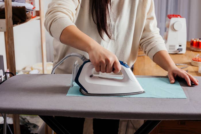 A woman irons a piece of fabric.