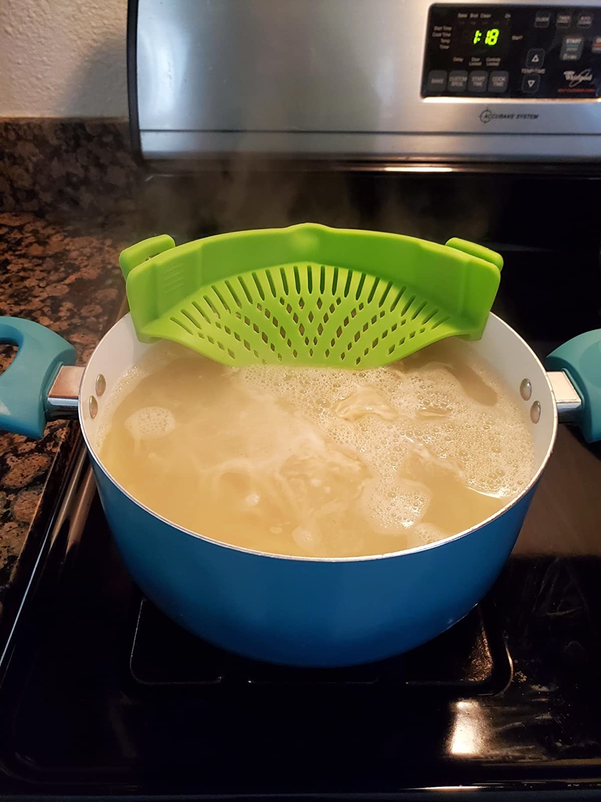Reviewer photo of the green strainer attached to a pot full of water and pasta