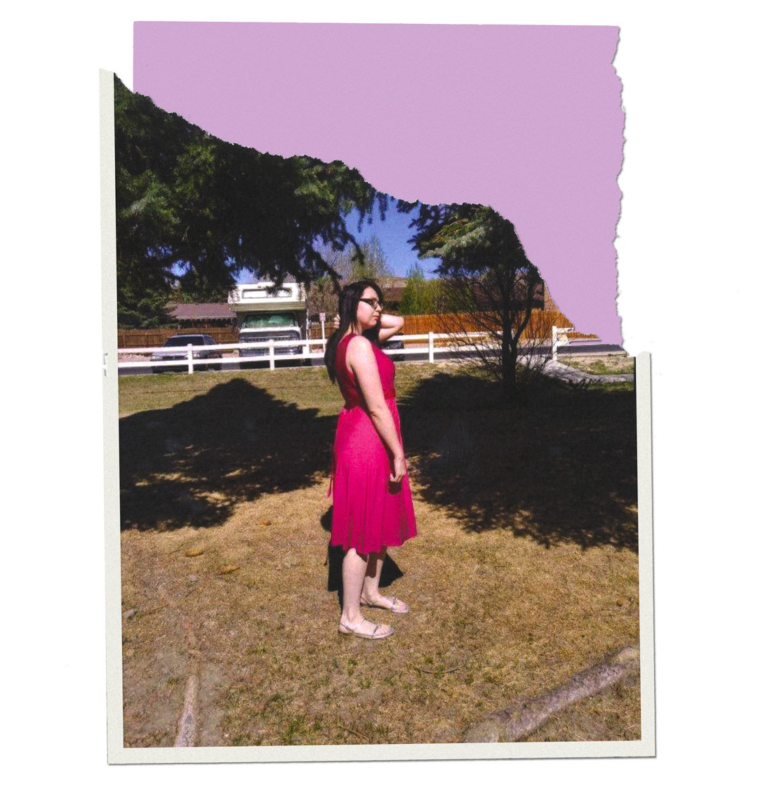 Arieana standing on grass in a dress and sandals and touching her hair