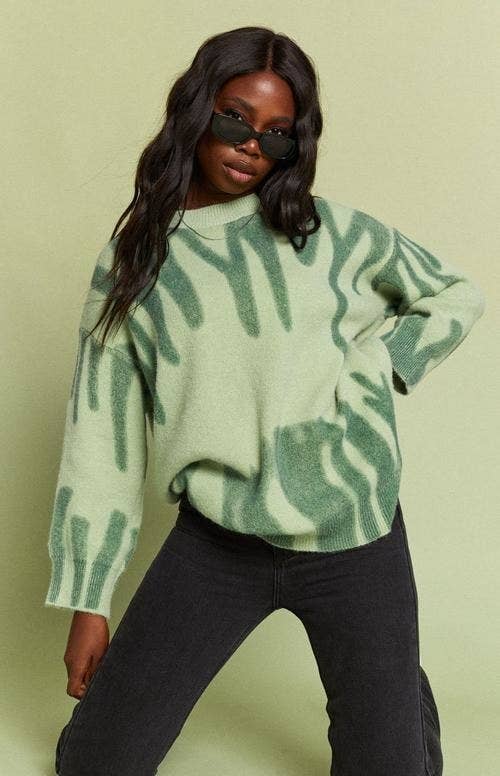 a model in a mint green sweater with abstract green designs on it