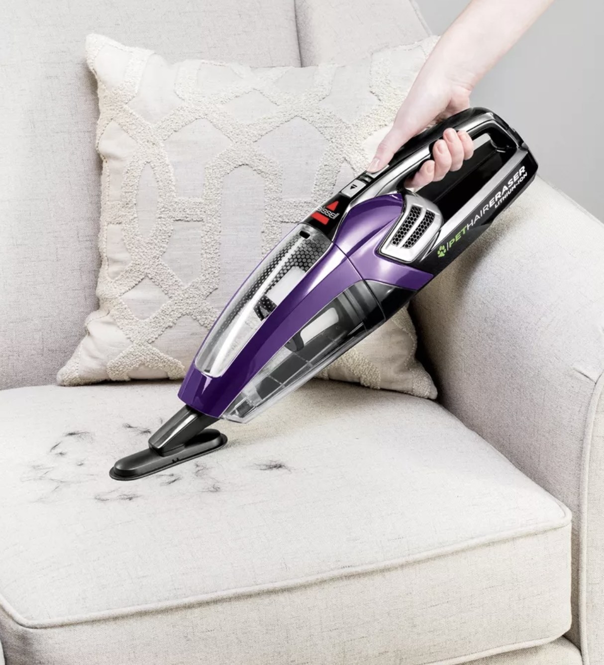 a handheld vacuum cleaning pet hair off a couch