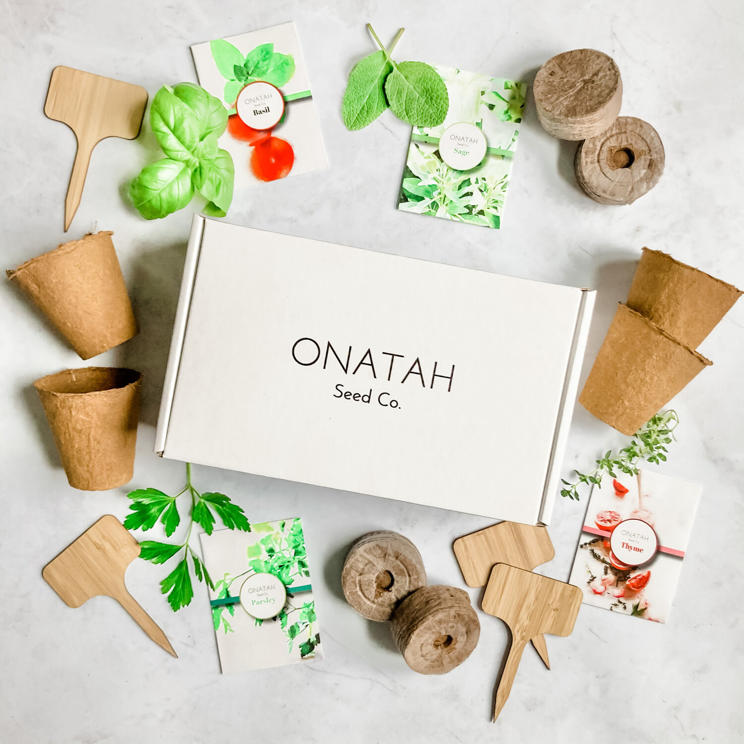 A white box that says Onatah Seed Co. on the front surrounded by garden tools