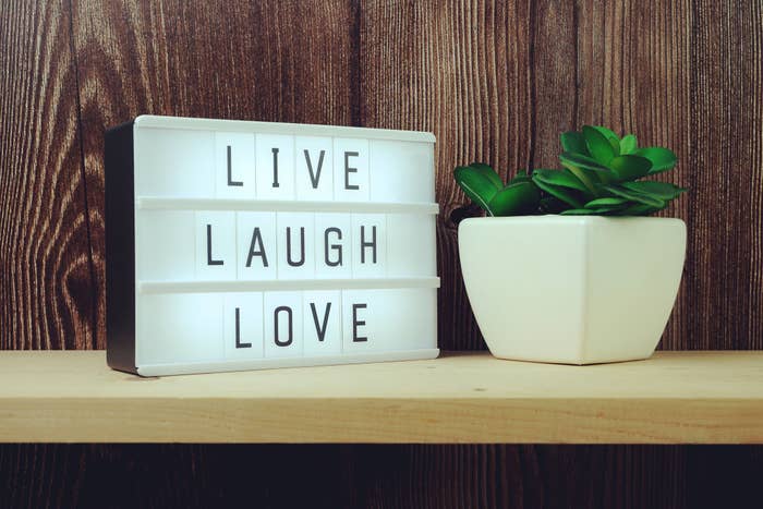 &quot;Live Laugh Love&quot; illuminated next to a plant on a shelf