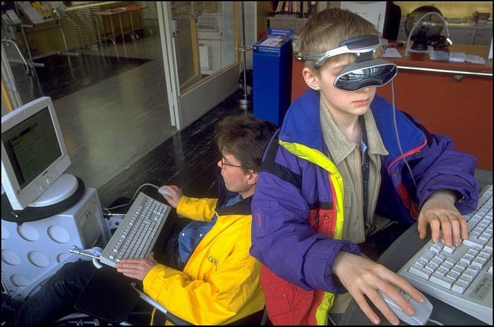 Kid sitting at a computer with a colorful jacket and glasses