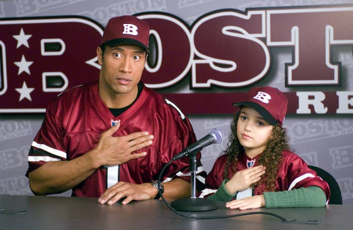 The Rock and young madison at a press conference with their hands over their heards in the game plan