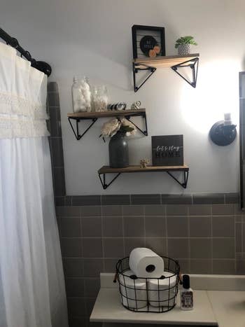reviewer pic of the three shelves above a counter in a bathroom