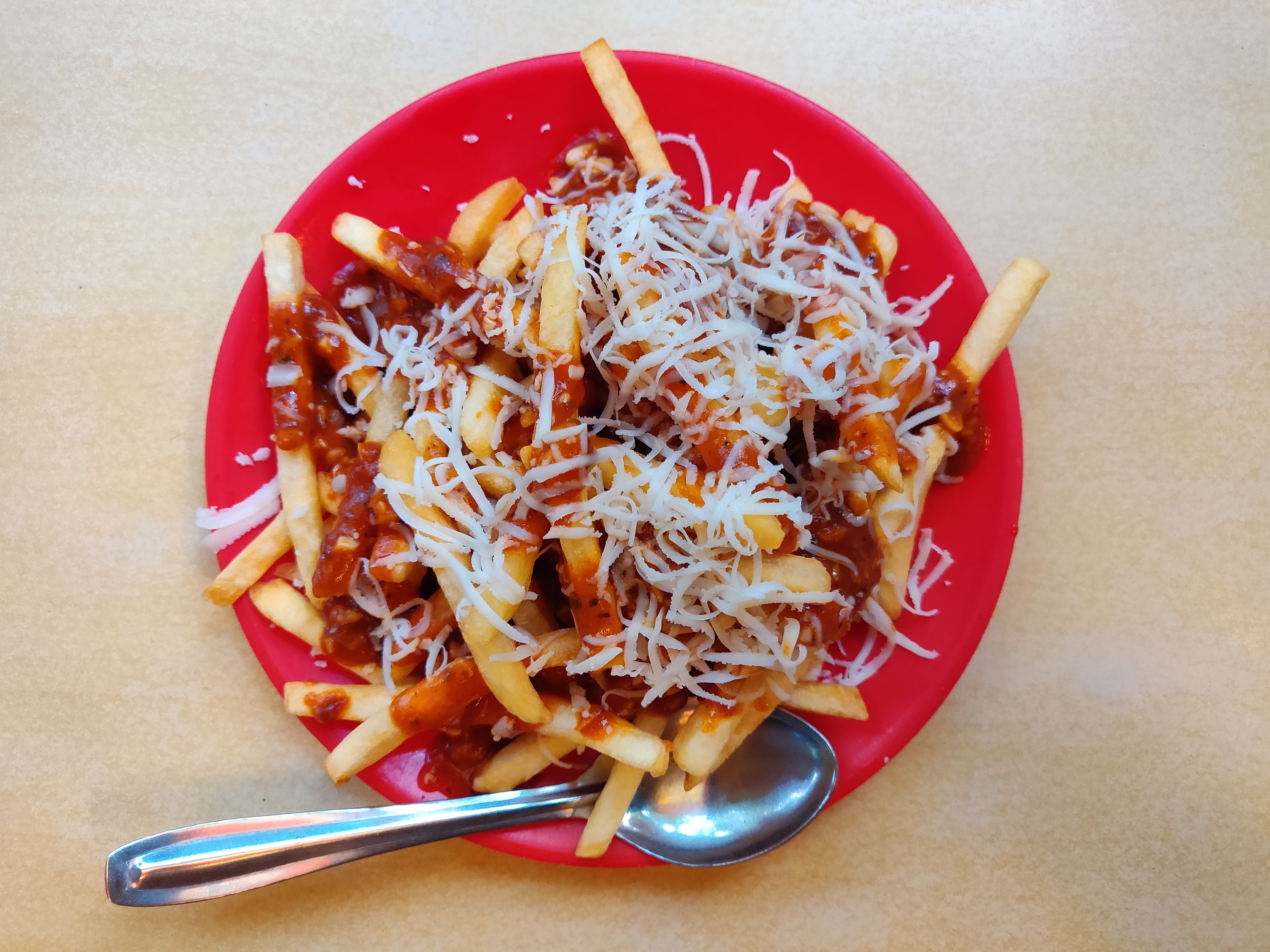 Fries topped with a red sauce and grated cheese