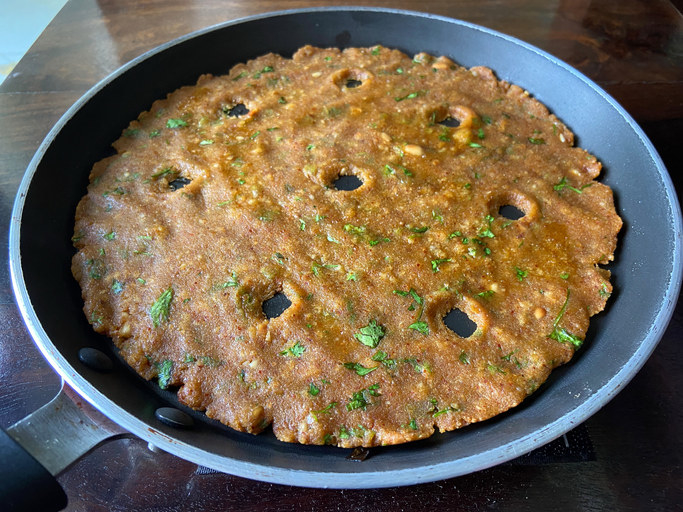 A thaalipeeth kept on a frying pan.