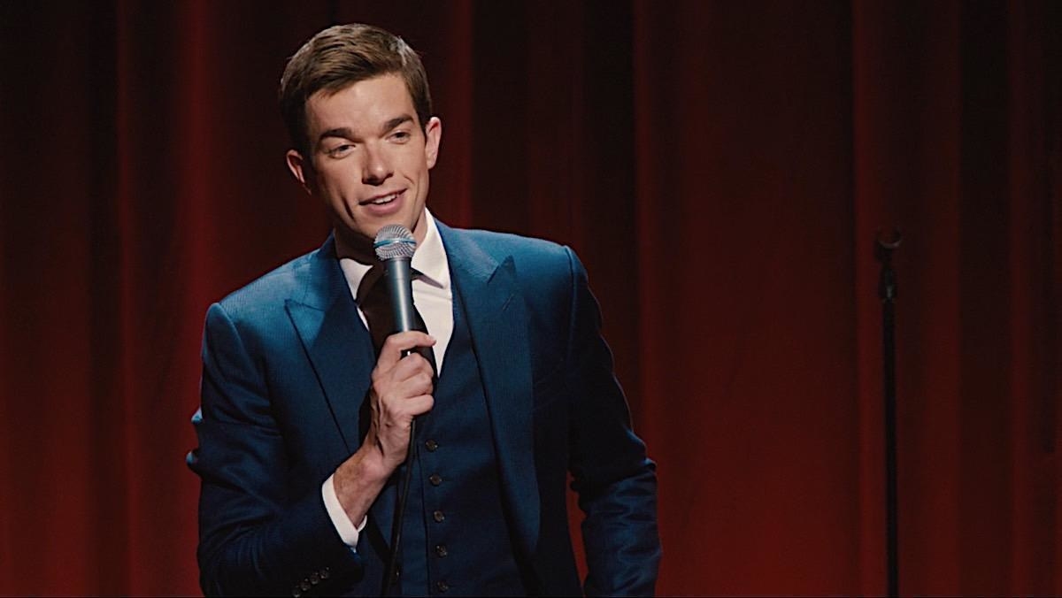 John Mulaney performing standup in a blue suit
