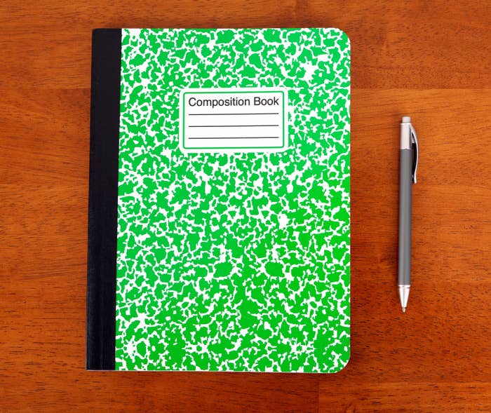 Green composition notebook with a pen next to it
