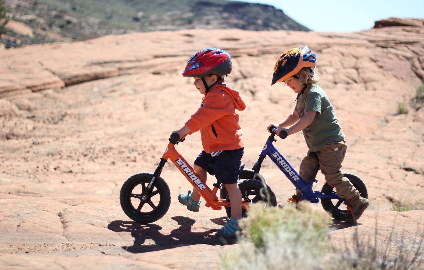 Two kids riding balance bike outdoors