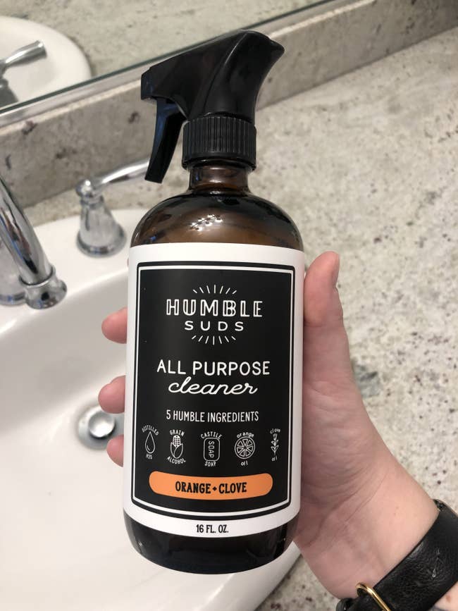 A BuzzFeed writer holds up the all purpose cleaner in a bathroom