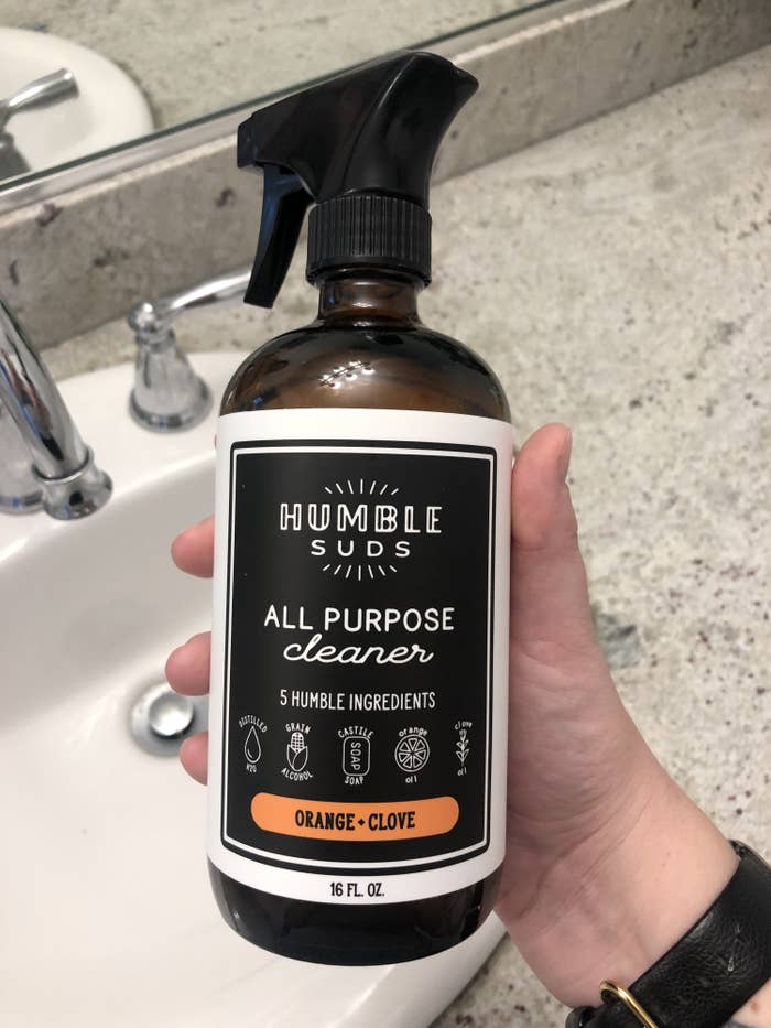 A person holds up the all purpose cleaner in a bathroom