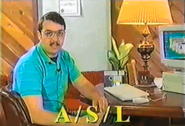 A man with a mustache sitting in front of a computer with &quot;A/S/L&quot; written on the screen