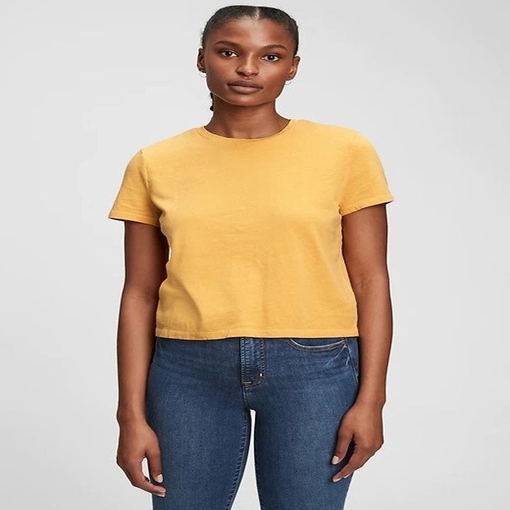 model in yellow baby tee and jeans