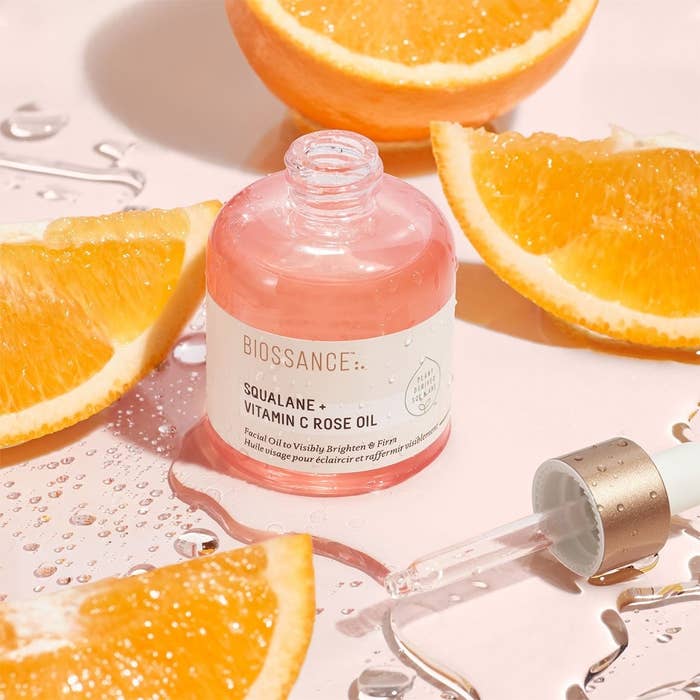 bottle of Biossance Squalane + Vitamin C Rose Oil next to orange slices