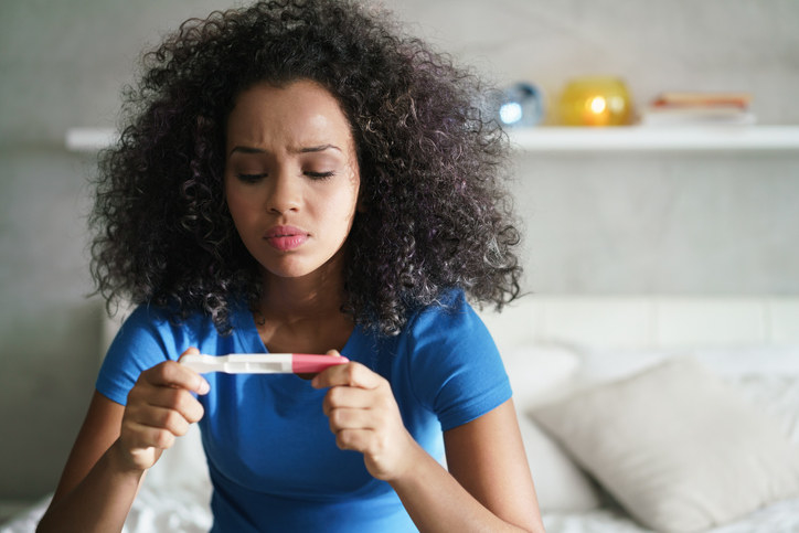 Woman looking at a pregnancy test with concern
