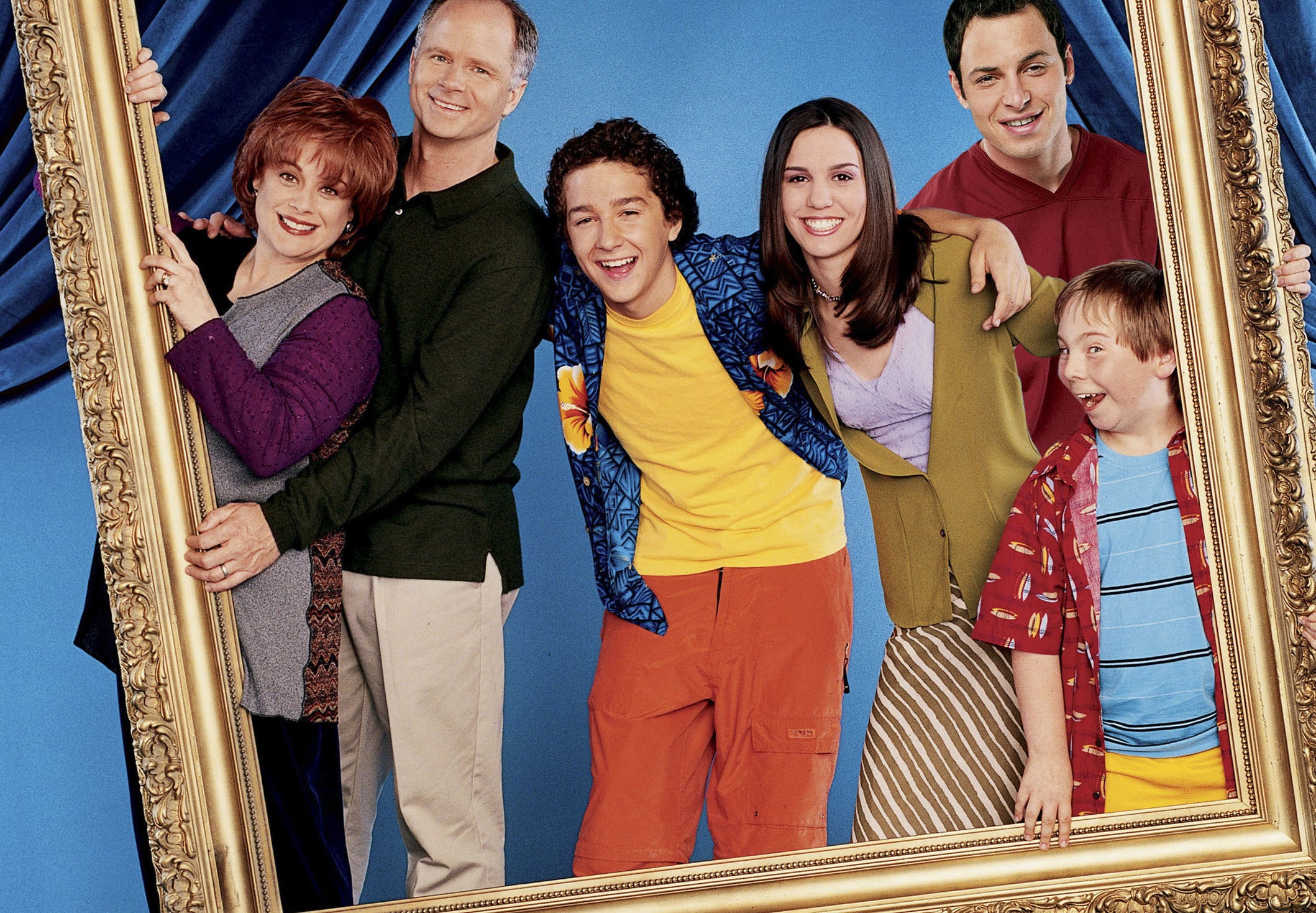 Christy poses with the Even Stevens cast in the middle of a giant frame they are holding up