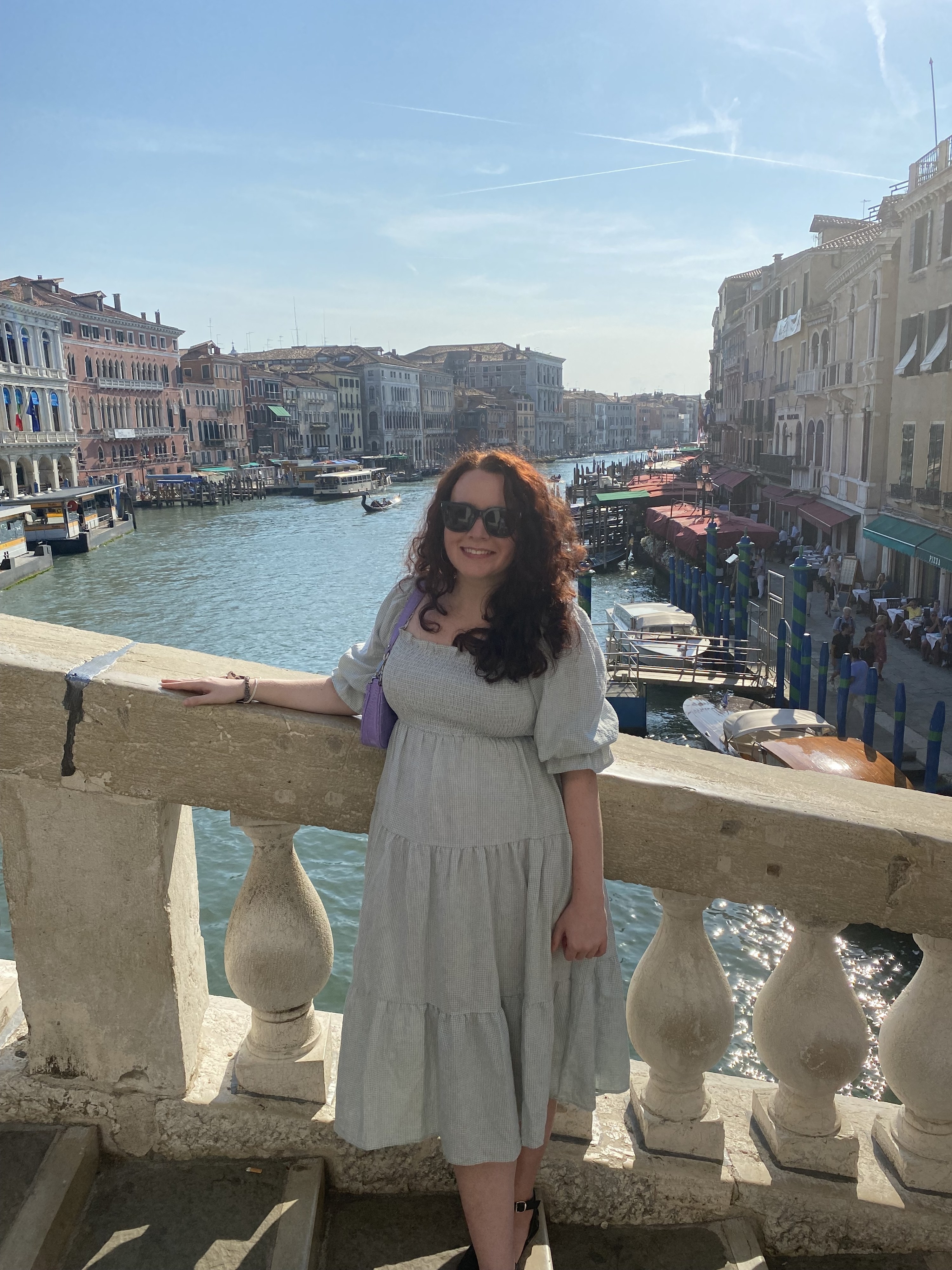 writer wearing elbow length sleeve gingham print midi dress on a bridge in Venice Italy