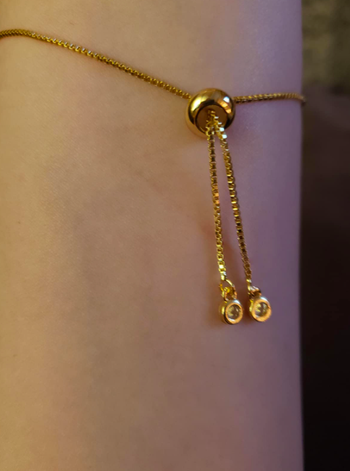 reviewer's wrist showing the closure part of the bracelet which has a small golden loop that pulls the bracelet tight