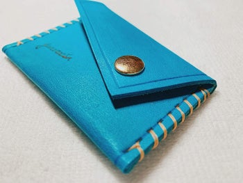 square leather card holder in a turquoise color with an asymmetrical flap closure