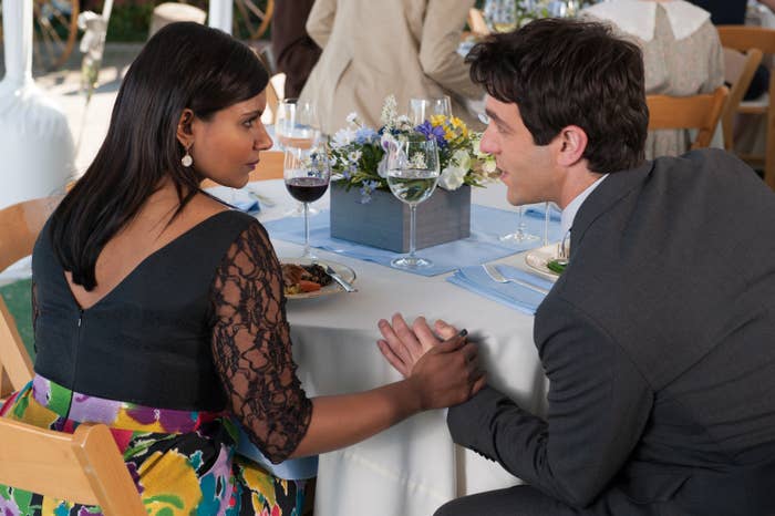 B.J.'s character from The Office sits at a dining table with Mindy Kaling's character