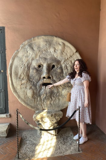writer wearing the same dress with hand stuck in mouth of a statue