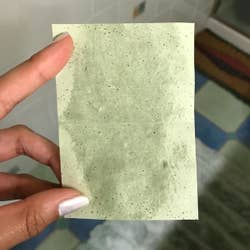 reviewer holding the blotting sheet with removed oil 
