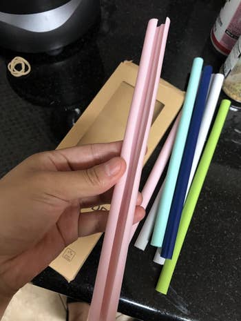 reviewer photo of the pink silicone straw being opened for cleaning