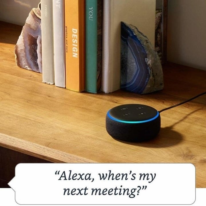 the echo dot in black with a speech bubble that says "alexa, when's my next meeting?"