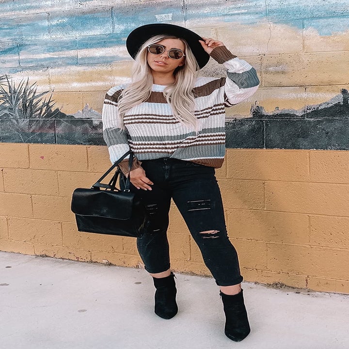 reviewer wearing a white, teal, and brown striped sweater with jeans and booties 