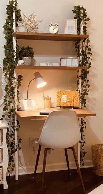 three tier storage desk mounted to the wall with faux vines on either side 