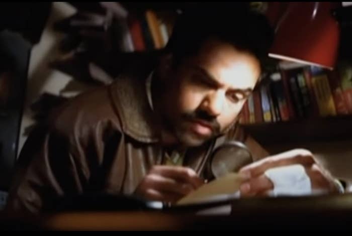 Abhay Deol peering over a piece of paper with a magnifying glass