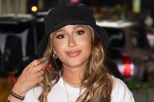 an image of adrienne bailon wearing a bucket hat and a white shirt while walking outside 
