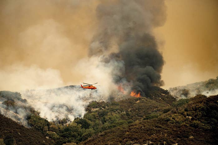 A helicopter flies over a forest fire