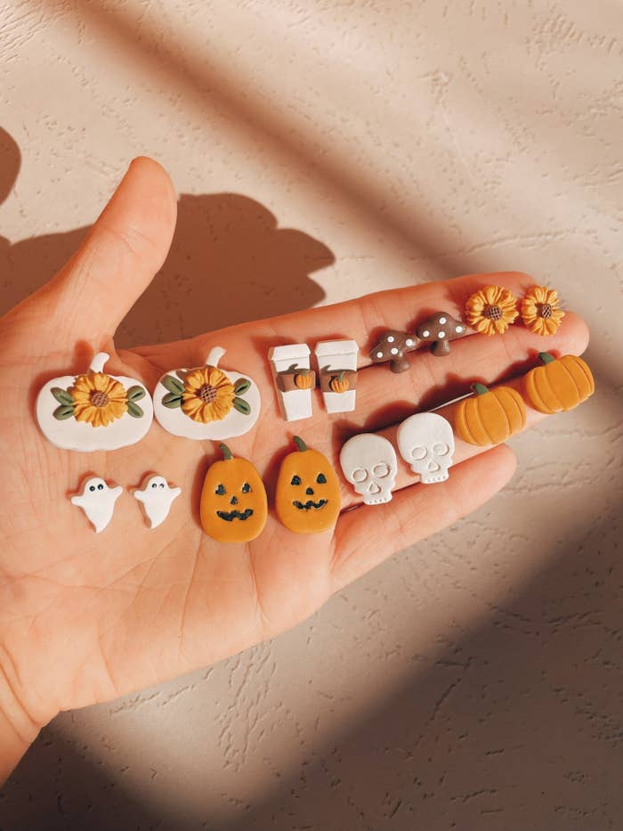 palm holding stud earrings of fall-centric things like pumpkins and ghosts